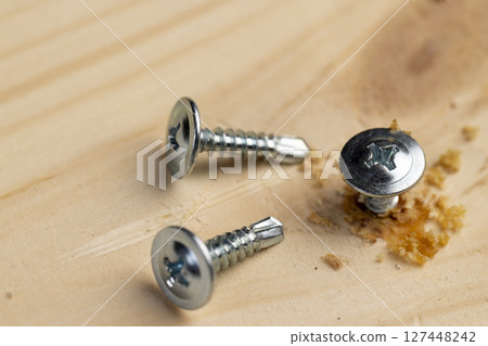 silver self-tapping screws for wood on the board, closeup silver self-tapping screws for wood on the board, closeup 127448242