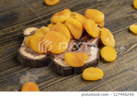 dried apricots are dehydrated after removing the seeds, apricots on a wooden board, close up, side view 127448248