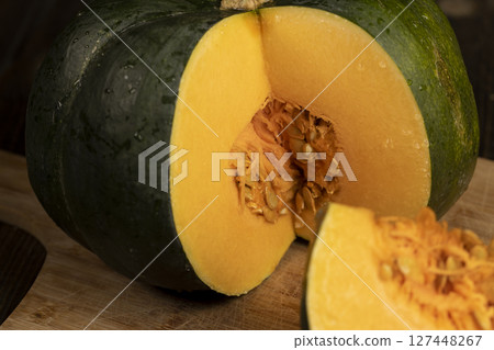 cut orange ripe pumpkin for cooking, cut into pieces sweet pumpkin in the kitchen, close up 127448267