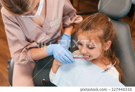 Woman teaching little girl how to brush teeth. In the stomatological cabinet Woman teaching little girl how to brush teeth. In the stomatological cabinet 127448338