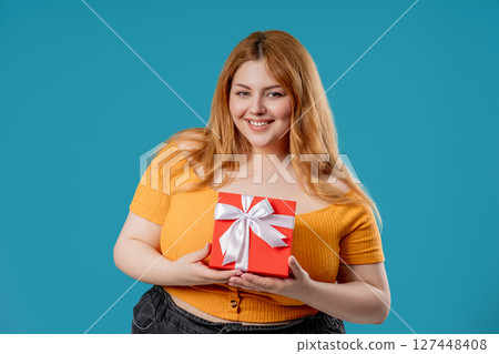 Happy body positive woman with Gift Box On Blue Background. Full figured lady Happy body positive woman with Gift Box On Blue Background. Full figured lady 127448408