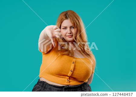 Plus Size Woman With Dislike. Grimacing Condemning Curvy Lady Shows Thumbs-Down  127448457