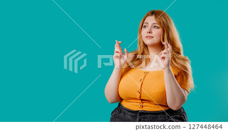 Curvy woman praying with crossed fingers, blue background. Lady begs someone, satisfy desires, help Curvy woman praying with crossed fingers, blue background. Lady begs someone, satisfy desires, help 127448464
