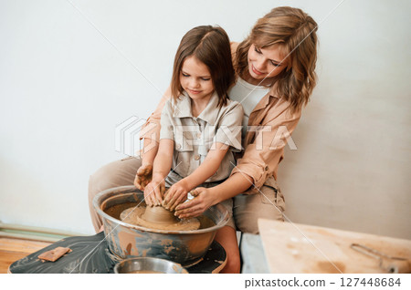 Creating the pot. Mother with little girl doing pottery at home Creating the pot. Mother with little girl doing pottery at home 127448684