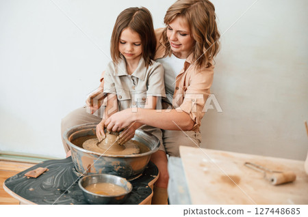 Creating the pot. Mother with little girl doing pottery at home Creating the pot. Mother with little girl doing pottery at home 127448685