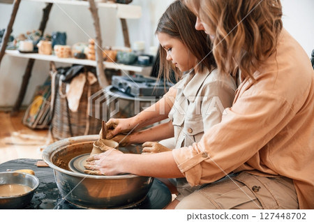 Teaching the art of pottery. Mother with little girl in the workshop Teaching the art of pottery. Mother with little girl in the workshop 127448702