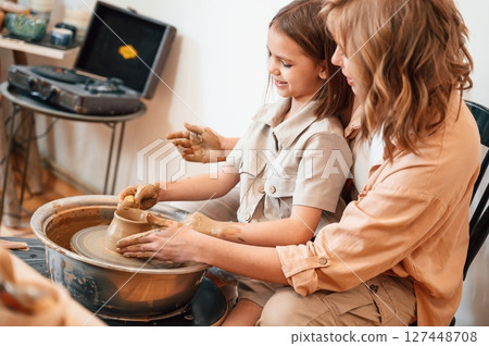 Sitting, creating the shape. Mother with little girl doing pottery at home Sitting, creating the shape. Mother with little girl doing pottery at home 127448708