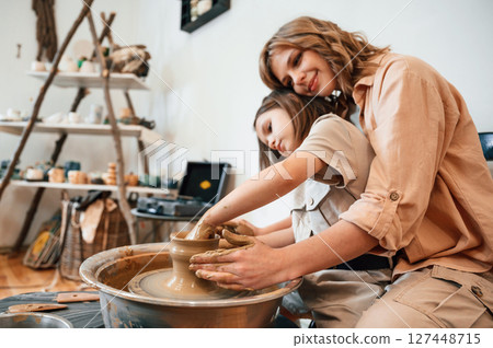 Having fun by making the ceramic pot. Mother with little girl is in the workshop Having fun by making the ceramic pot. Mother with little girl is in the workshop 127448715
