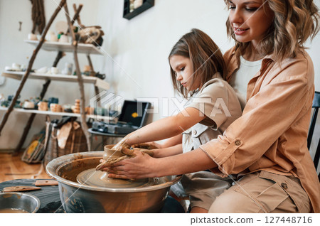 In the workshop. Mother with little girl making ceramic pot In the workshop. Mother with little girl making ceramic pot 127448716