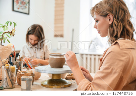 Mother with little girl making ceramic pot in the workshop Mother with little girl making ceramic pot in the workshop 127448736