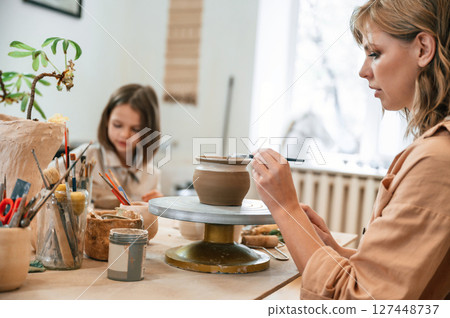 Mother with little girl making ceramic pot in the workshop Mother with little girl making ceramic pot in the workshop 127448737