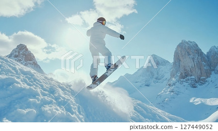 Snowboarder jumping on snowy mountain slope on sunny day 127449052