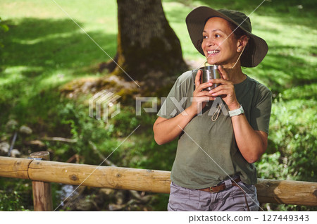 Woman Enjoying the Outdoors With a Cup of Drink in a Sunny Park 127449343