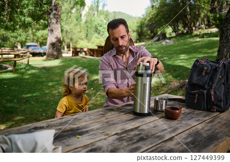 Father with Child Relaxing Outdoors in Scenic Nature at Picnic Scene 127449399