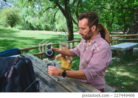 Man Enjoying an Outdoor Picnic in Nature with Family at a Scenic Park Man Enjoying an Outdoor Picnic in Nature with Family at a Scenic Park 127449406
