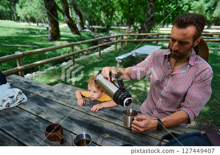 Father and Child Enjoying a Relaxing Outdoor Picnic Amidst Nature Father and Child Enjoying a Relaxing Outdoor Picnic Amidst Nature 127449407