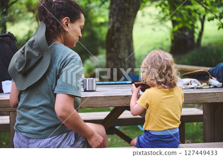 Mother and Child Enjoying Outdoor Moments at a Picnic Table in Nature 127449433