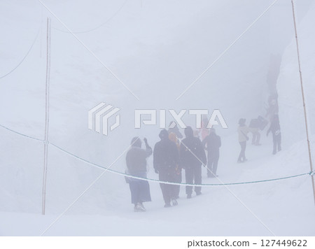 Tourists at Murodo on the tourist attraction Tateyama Kurobe Alpine Route during a snowstorm 127449622