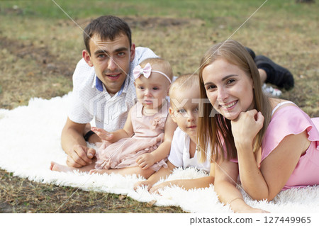 Husband and wife and their little children. Family portrait in nature. Mom and Dad are holding a brother and sister in their arms. Young family with children for a walk. Husband and wife and their little children. Family portrait in nature. Mom and Dad are holding a brother and sister in their arms. Young family with children for a walk. 127449965
