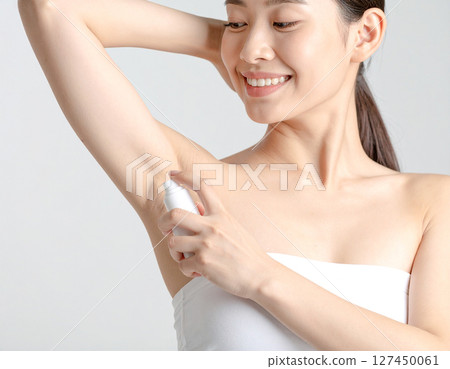 A woman uses a deodorant spray to combat underarm odor 127450061
