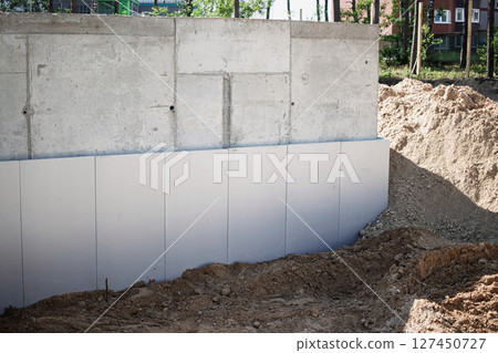 Construction site showing newly installed concrete wall and ground preparation for building foundations Construction site showing newly installed concrete wall and ground preparation for building foundations 127450727