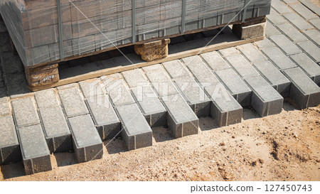 Construction site with stacked pavers and completed pavement during daylight 127450743