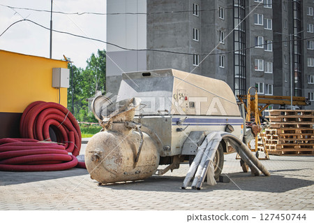 Construction equipment and materials at a building site near a residential area in bright daylight 127450744