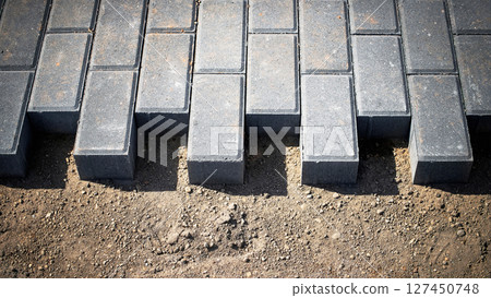 New paving stones laid in a concrete pathway under bright sunlight at a construction site 127450748