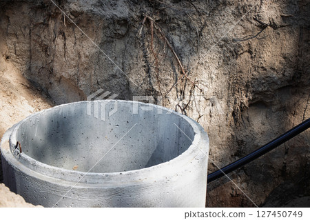 Construction site showing a concrete well casing in a dug area surrounded by dirt and roots Construction site showing a concrete well casing in a dug area surrounded by dirt and roots 127450749