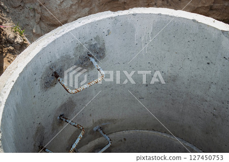 Construction site showing a concrete well with exposed rebar under a bright sky at midday 127450753