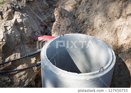 Construction work in progress at a deep trench for sewer system installation near a rural area 127450755