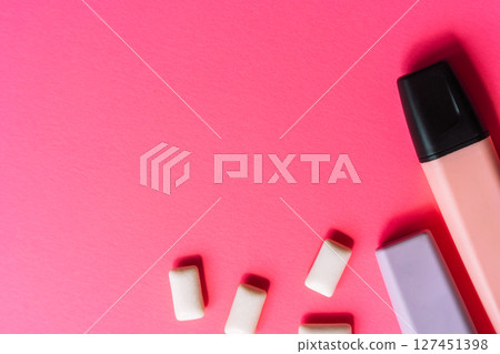 Chewing gum, a pink highlighter, and a purple eraser on a vibrant pink background. Flat lay with bold Gen Z aesthetic. 127451398