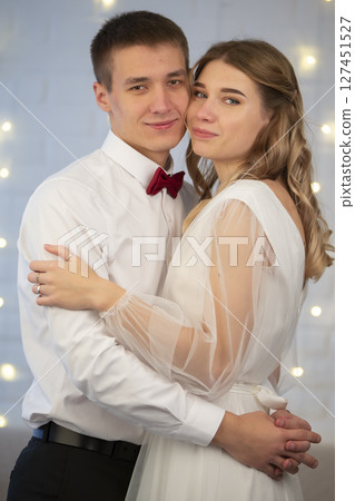On a gray background, the bride and groom look at each other. Beautiful couple in love. On a gray background, the bride and groom look at each other. Beautiful couple in love. 127451527
