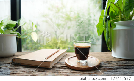 Coffee and brown notebook on rustic wood table by the window 127451537