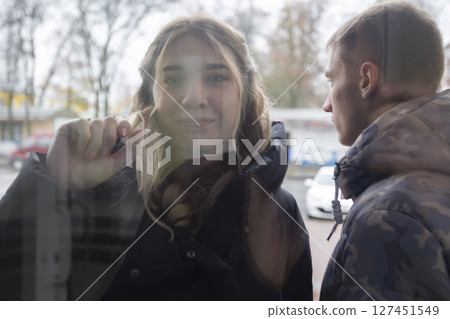 A young girl knocks her fist on the glass door. 127451549