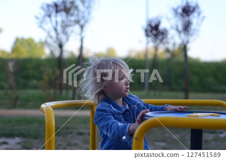 Cute Girl Enjoying Carousel Ride at Playground 127451589