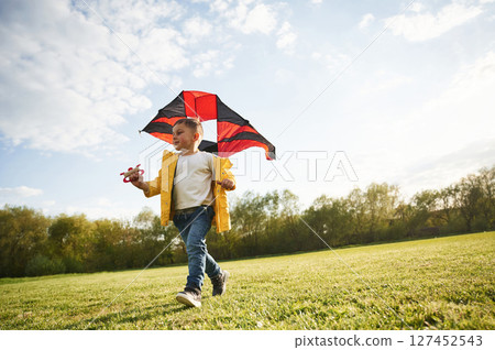 On green meadow. Little boy is playing with a kite On green meadow. Little boy is playing with a kite 127452543