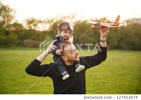 Father with his little son playing with toy plane on the field Father with his little son playing with toy plane on the field 127452674
