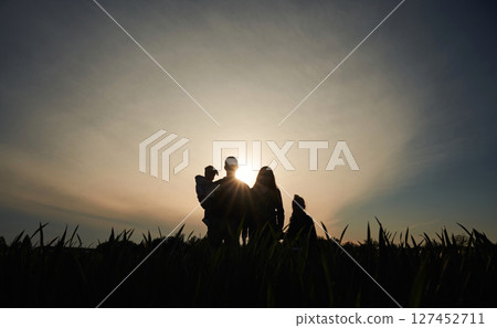 Silhouette of couple with children in the field. Amazing sunshine. Dark photo 127452711