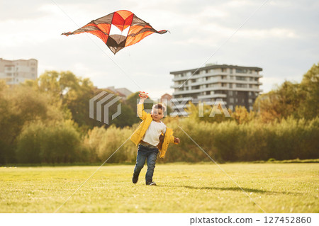 Running with kite. Little boy is playing on the field at summer time 127452860
