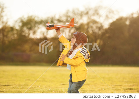Toy plane. Little boy is playing on the summer field 127452868