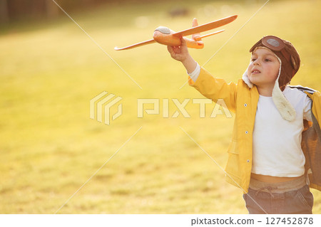 Retro style aviator glasses. Little boy is playing with toy plane on the summer field 127452878