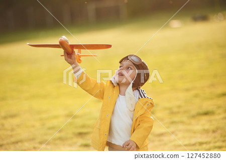 Retro style aviator glasses. Little boy is playing with toy plane on the summer field 127452880