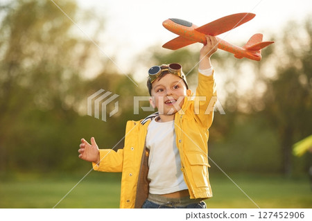 Focused view with background. Little boy is playing with toy plane on the summer field 127452906