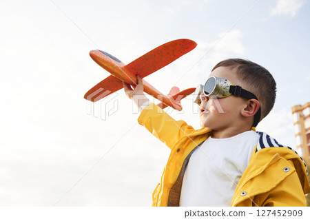 Red colored toy plane. Little boy is playing on the summer field 127452909