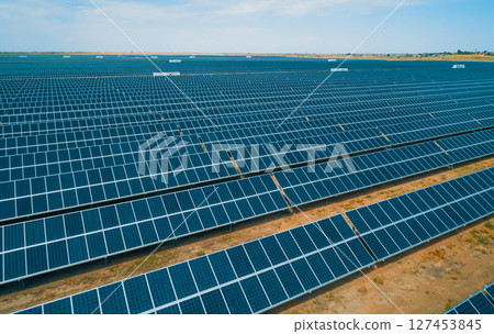 Expansive solar panel arrays under a clear blue sky in a vast renewable energy farm 127453845