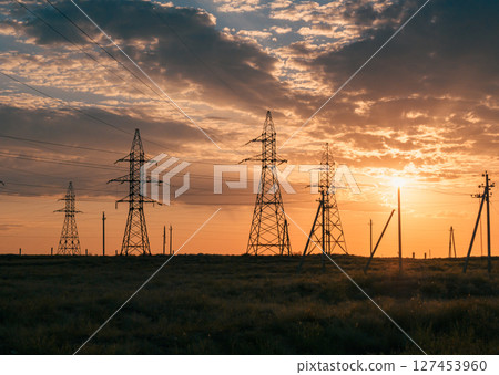 Sunset sky with power lines stretching over a desert landscape. Sunset sky with power lines stretching over a desert landscape. 127453960