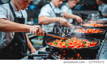 Young chefs cooking vibrant vegetables in a busy kitchen with dynamic culinary action 127454172