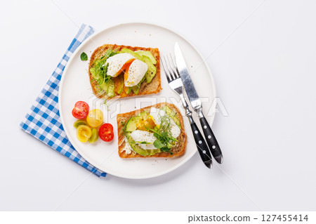 Delicious avocado toasts topped with perfectly cooked poached eggs Delicious avocado toasts topped with perfectly cooked poached eggs 127455414