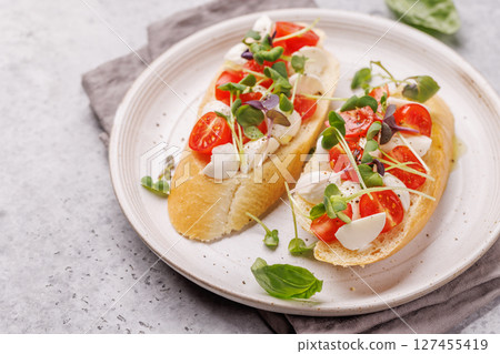 Tasty antipasto toasts featuring classic caprese with mozzarella and tomatoes, and savory prosciutto with herbs 127455419